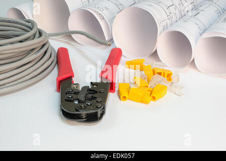 Drawing rolls, cat 5 cable, crimping pliers, connectors and boot caps composition Stock Photo