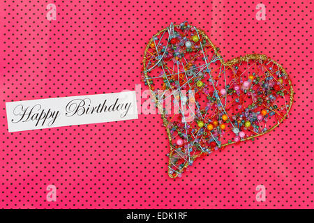 Happy Birthday card with heart made of colorful beads on pink dotty background Stock Photo