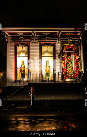 Illuminated Christmas decorations hang around the windows of a house in New Orleans LA at night Stock Photo