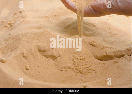 Mans hand with soft sand running through fingers. Stock Photo