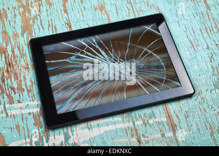 Digital Tablet Computer with Broken Screen on old wooden table. Stock Photo