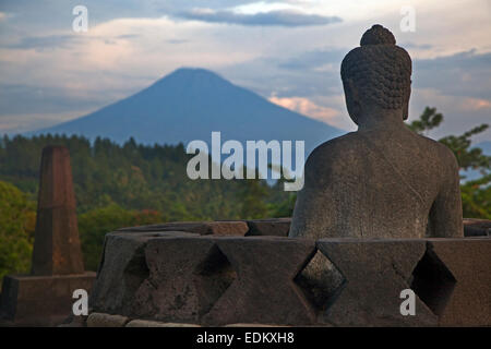 Buddha statue facing volcano at Borobudur / Barabudur, 9th-century Mahayana Buddhist Temple in Magelang, Central Java, Indonesia Stock Photo