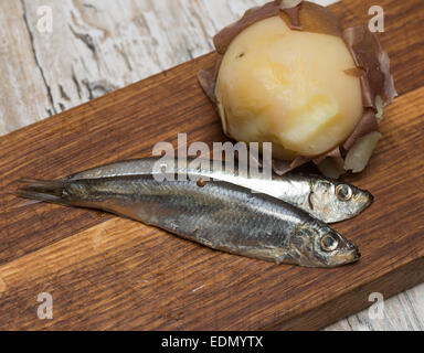 spicy salted anchovies and boiled potatoes on a wooden board Stock Photo