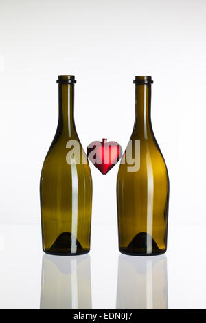 Empty bottles of wine and red heart on a glass table Stock Photo