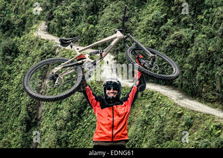 Mountain biker pulls up his mountain bike at the famous downhill trail 'Road of death' in Bolivia. Stock Photo