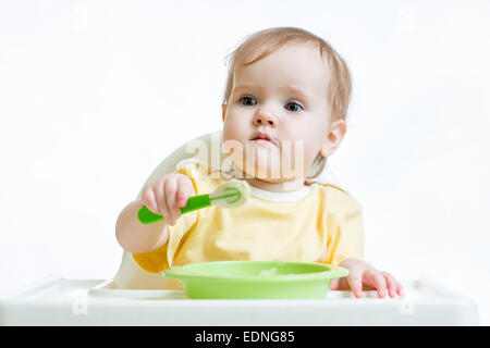 baby child sitting in chair with a spoon Stock Photo