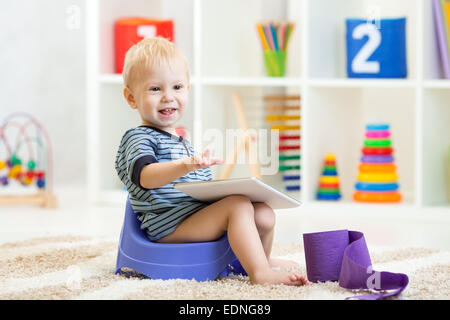 smiling child sitting on chamber pot indoor Stock Photo