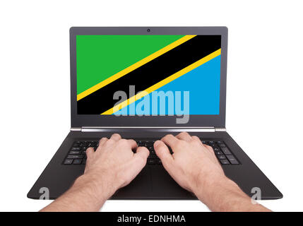 Hands working on laptop showing on the screen the flag of Tanzania Stock Photo