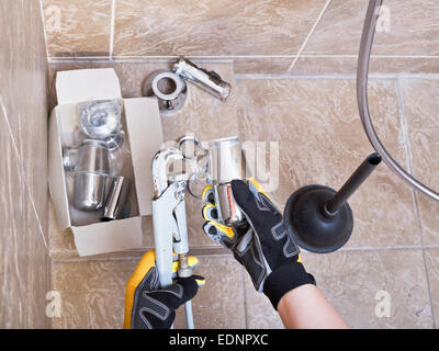 plumber repairs sink chrome plated trap in bathroom Stock Photo
