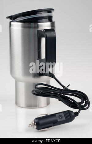 12 volt car adapter cable plugged into a  stainless mug for heating Stock Photo