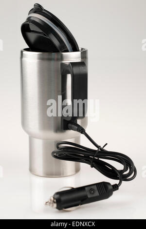 12 volt car adapter cable plugged into a  stainless mug for heating Stock Photo