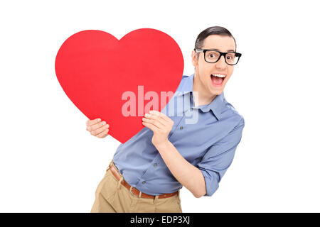 Joyful young man holding a big red heart isolated on white background Stock Photo