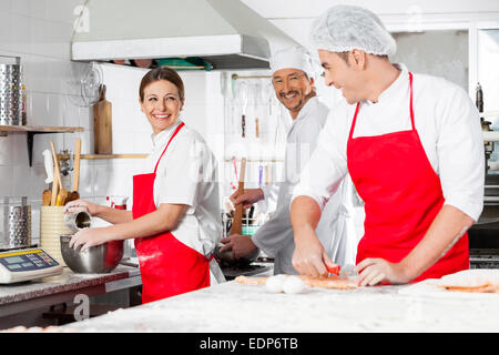 Happy Chefs Conversing In Commercial Kitchen Stock Photo