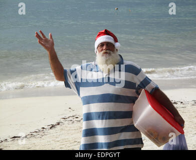 Elderly man dressed in Santa's hat on the beach in the Caribbean. Stock Photo