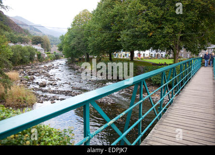 Walkers on the footbridge at the confluence of the Rivers Glaslyn and Colwyn in Beddgelert, Snowdonia, North Wales,UK Stock Photo