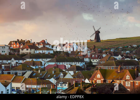 Rottingdean village, East Sussex, UK. 8th January, 2015. Starlings circle over Rottingdean in East Sussex in the last rays of sun. A panorama of the village, Beacon Mill (Rottingdean windmill) towers above on Beacon Hill, South Downs. Credit:  Slawek Staszczuk/Alamy Live News Stock Photo