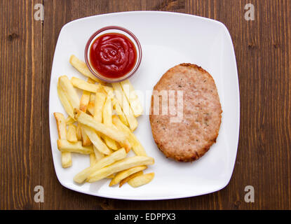 Hamburger with fries and ketchup on wooden table seen from above Stock Photo