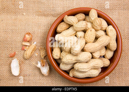 Peanuts in rustic bowl on jute mat seen from above Stock Photo
