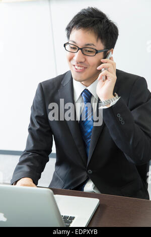 Businessman Talking on Mobile Phone and Using Computer Stock Photo