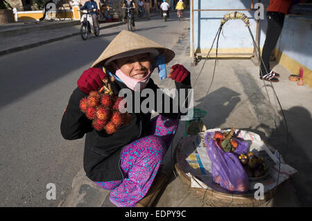 Vietnamese Woman with purple pants offering fruits in suburban Saigon Stock Photo