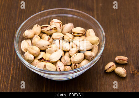 Pistachios on glass bowl on wooden table Stock Photo