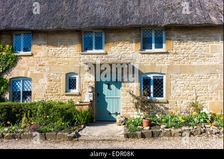 Quaint thatched cottage with traditional thatching and leaded light windows at Taynton in The Cotswolds, Oxfordshire, UK Stock Photo