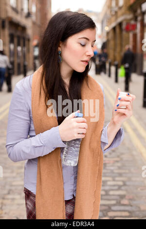 young woman taking her pilles in the street Stock Photo