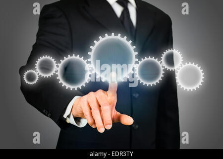 Businessman clicking on gears Stock Photo
