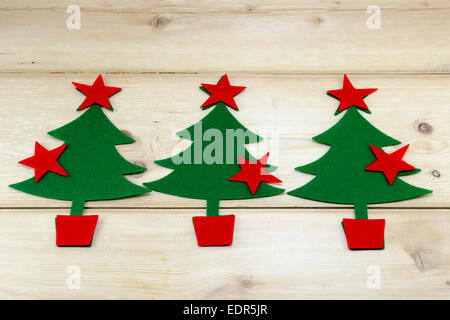 Three Christmas trees and stars on a wooden table Stock Photo