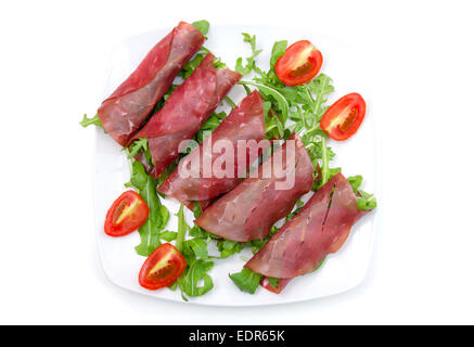 Rolls of dried beef on plate on white background seen from above Stock Photo