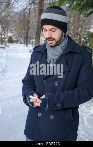 Young lumbersexual man texting in cold winter Stock Photo