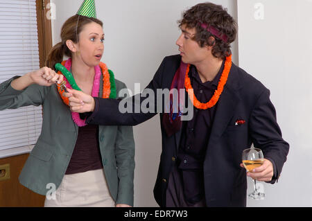 A woman at an office party taking car keys away from a disheveled looking man who has been drinking alcohol. Stock Photo