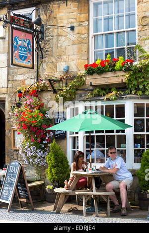Tourists drinking outdoors at The Cotswolds Arms inn traditional old gastro pub in Burford in The Cotswolds, Oxfordshire, UK Stock Photo