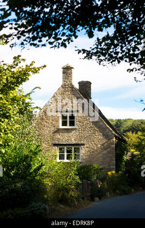 Traditional and typical old stone country cottage by country lane at Swinbrook in the Cotswolds, England, UK Stock Photo