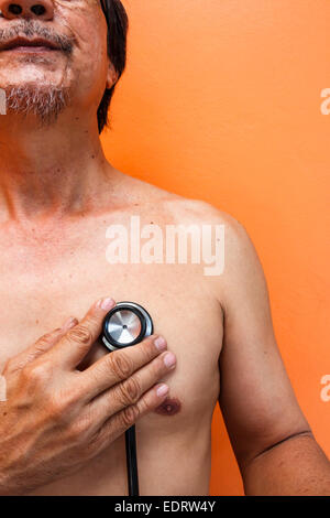 old aged asian man was diagnosed by doctor on orange background Stock Photo