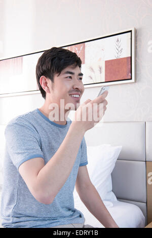 Young man sending voice message in bed Stock Photo