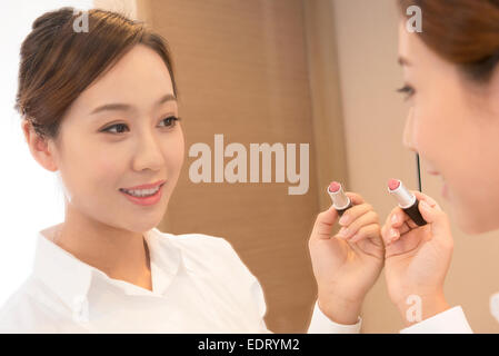 Young woman checking makeup in front of mirror Stock Photo