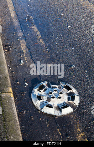 Wheel trim or cover lying at the side of the road after falling off a car, England, UK Stock Photo