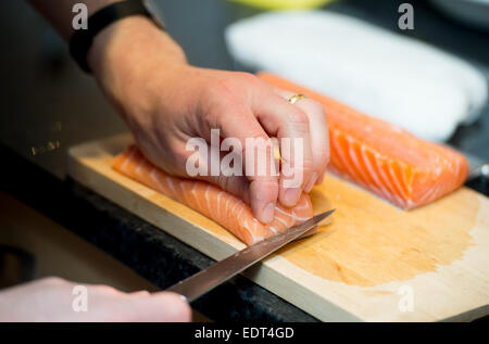 A man slicing a fillet of salmon whilst preparing sushi. Stock Photo