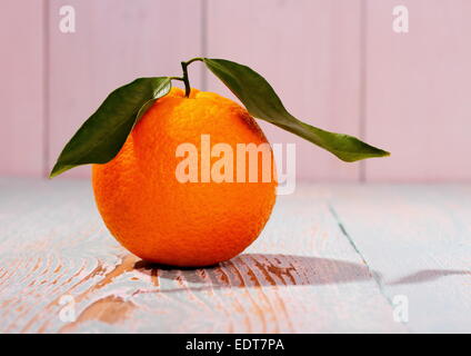 One big ripe orange fruit with leaf on wooden board, close up Stock Photo