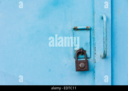 old padlock on a blue metal door Stock Photo