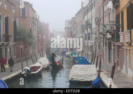 Winter in Venice - A gondola cruising down a canal in the fog. Stock Photo