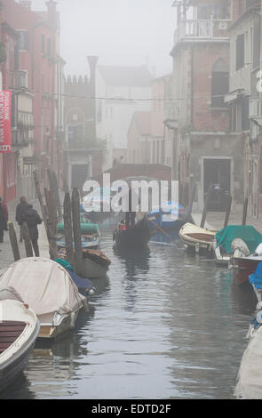 Winter in Venice - A gondola cruising down a canal in the fog. Stock Photo