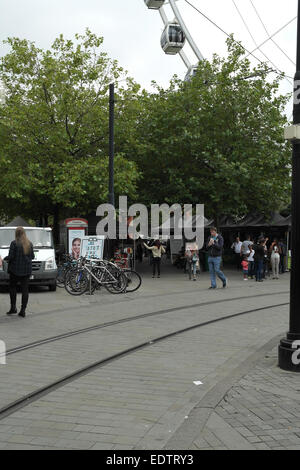 Grey sky portrait Market Street walkway tramway to people walking Piccadilly Street Food Market stalls below trees, Manchester Stock Photo