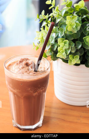 Cocoa milkshake on wood table with artificial plant Stock Photo
