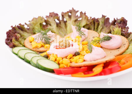 Cream, sweet corn and dill on crackers and vegetables in white plate. Stock Photo