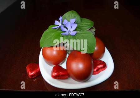 Colored eggs on white saucer with violet flowers. Stock Photo