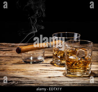 Whiskey drink with smoking cigar on wooden table Stock Photo