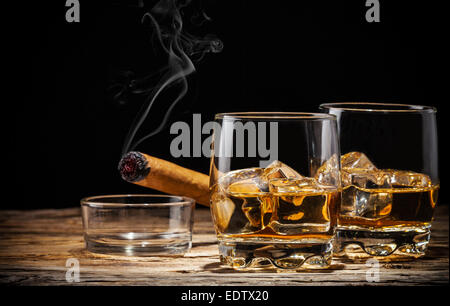 Whiskey drink with smoking cigar on wooden table Stock Photo