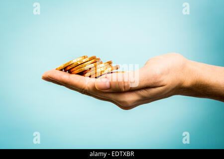 Hand holding golden coins concept on blue background. Business concept. Stock Photo